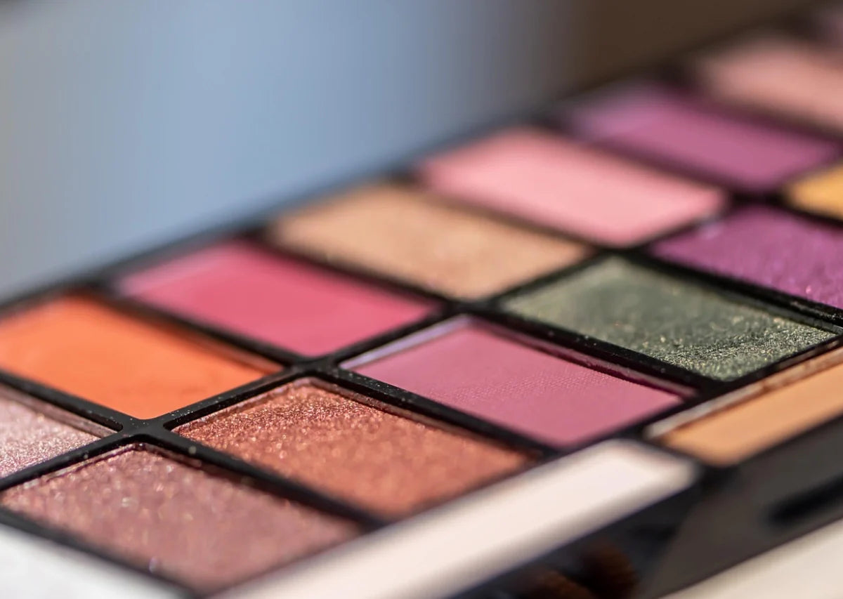 Close-up de una paleta de sombras con tonos rosados, dorados y verdes con acabado brillante y mate.